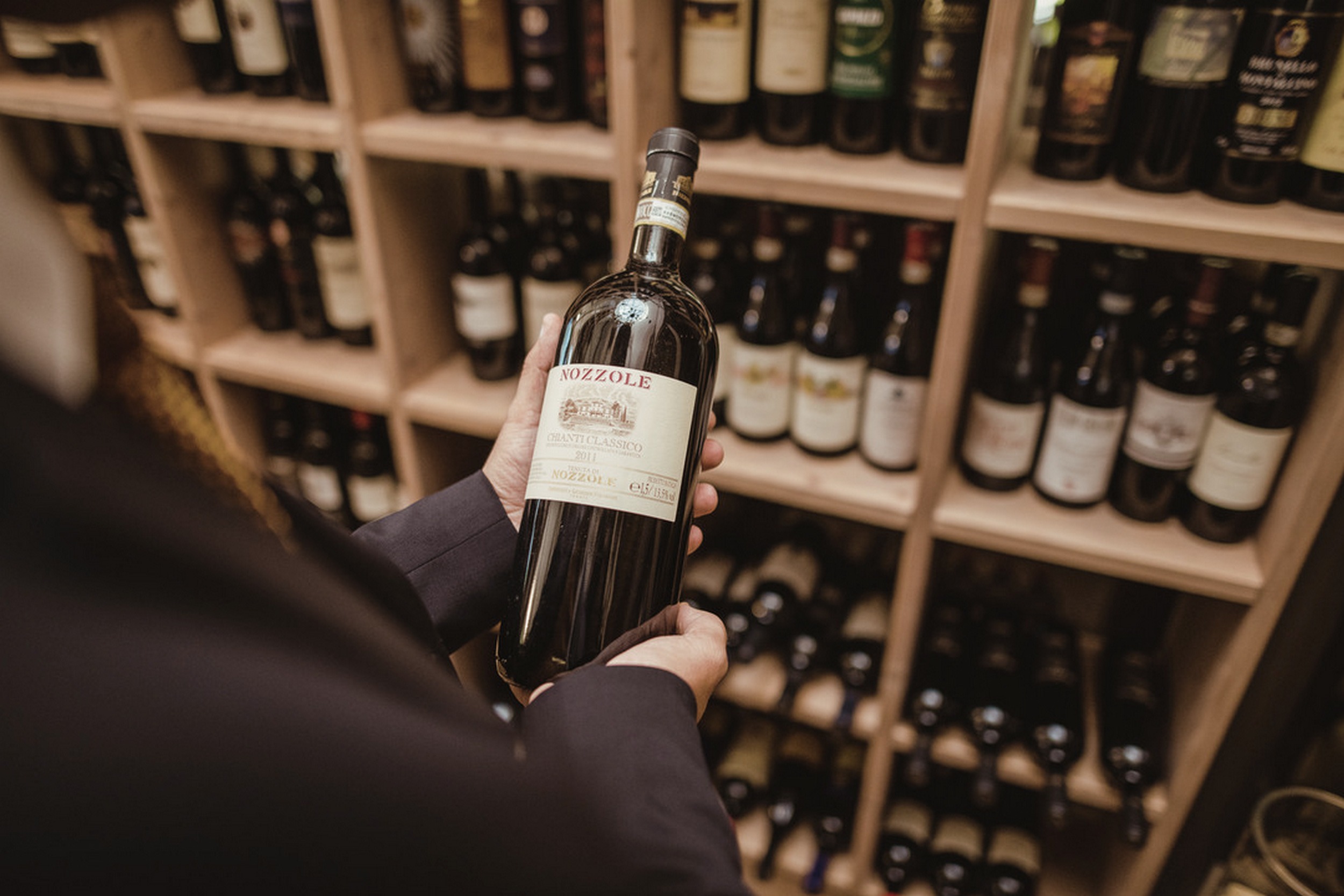 La Maiena Meran Resort in Marling – Hand hält eine Flasche Wein aus dem Weinkeller | Wellnesshotel Südtirol