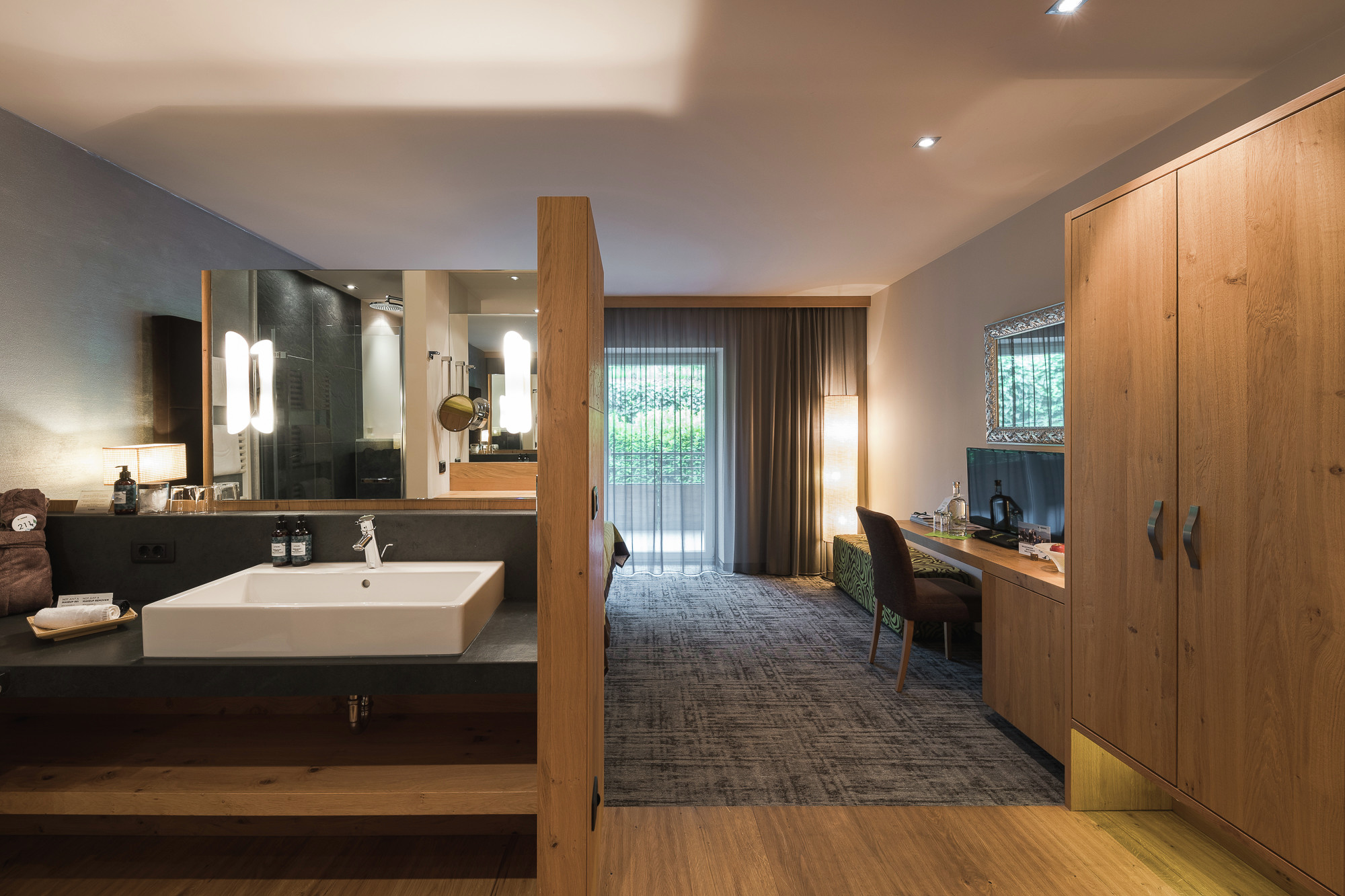 La Maiena Meran Resort in Marling – Modernes Badezimmer mit Waschtisch und Blick ins Schlafzimmer | Wellnesshotel Südtirol