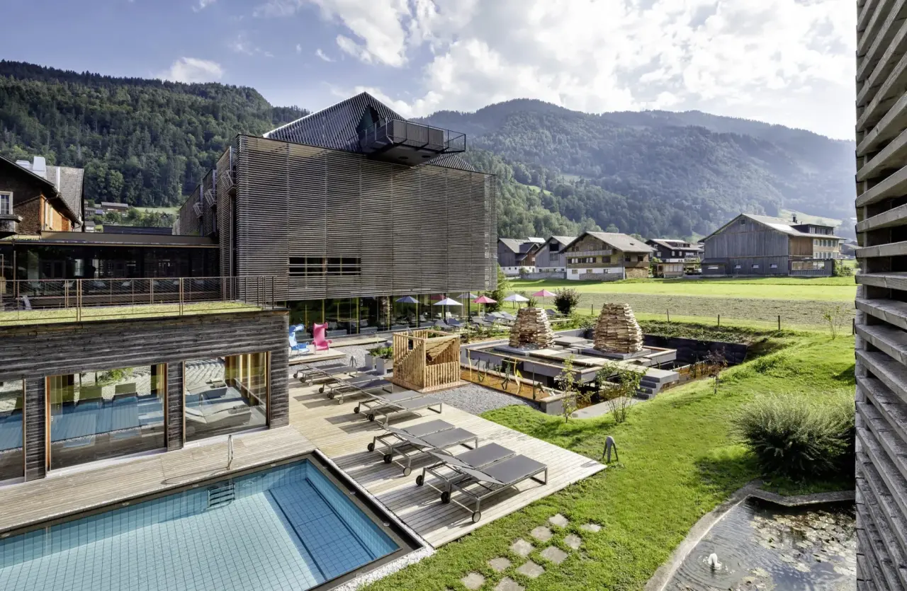 Moderner Aussenpool mit Holzdeck und Liegen vor dem Hotel GAMS zu zweit, umgeben von grünen Wiesen und Bergen.