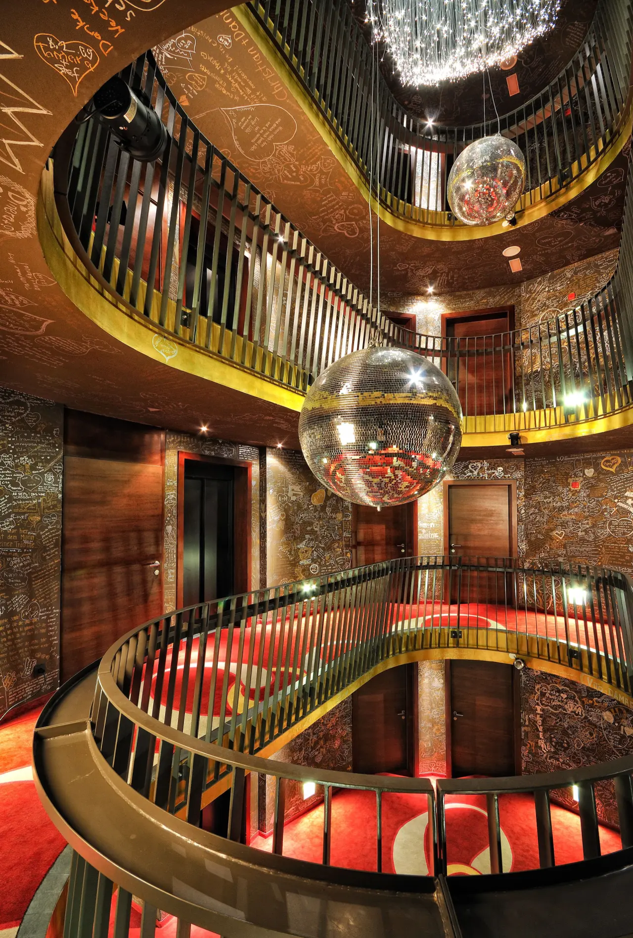 Einzigartiges Treppenhaus im Hotel GAMS zu zweit mit roten Teppichen, Gästenachrichten und funkelnden Discokugeln.