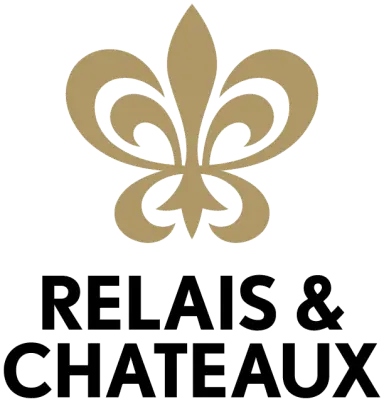 Logo von Relais & Châteaux Hotel Schwarzmatt mit goldener Fleur-de-lis und Schriftzug auf weissem Hintergrund.