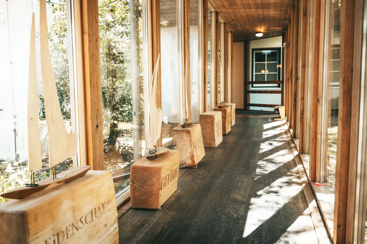 Heller Flur im Hotel Haferland mit Holzelementen, großen Fenstern und maritimer Dekoration.