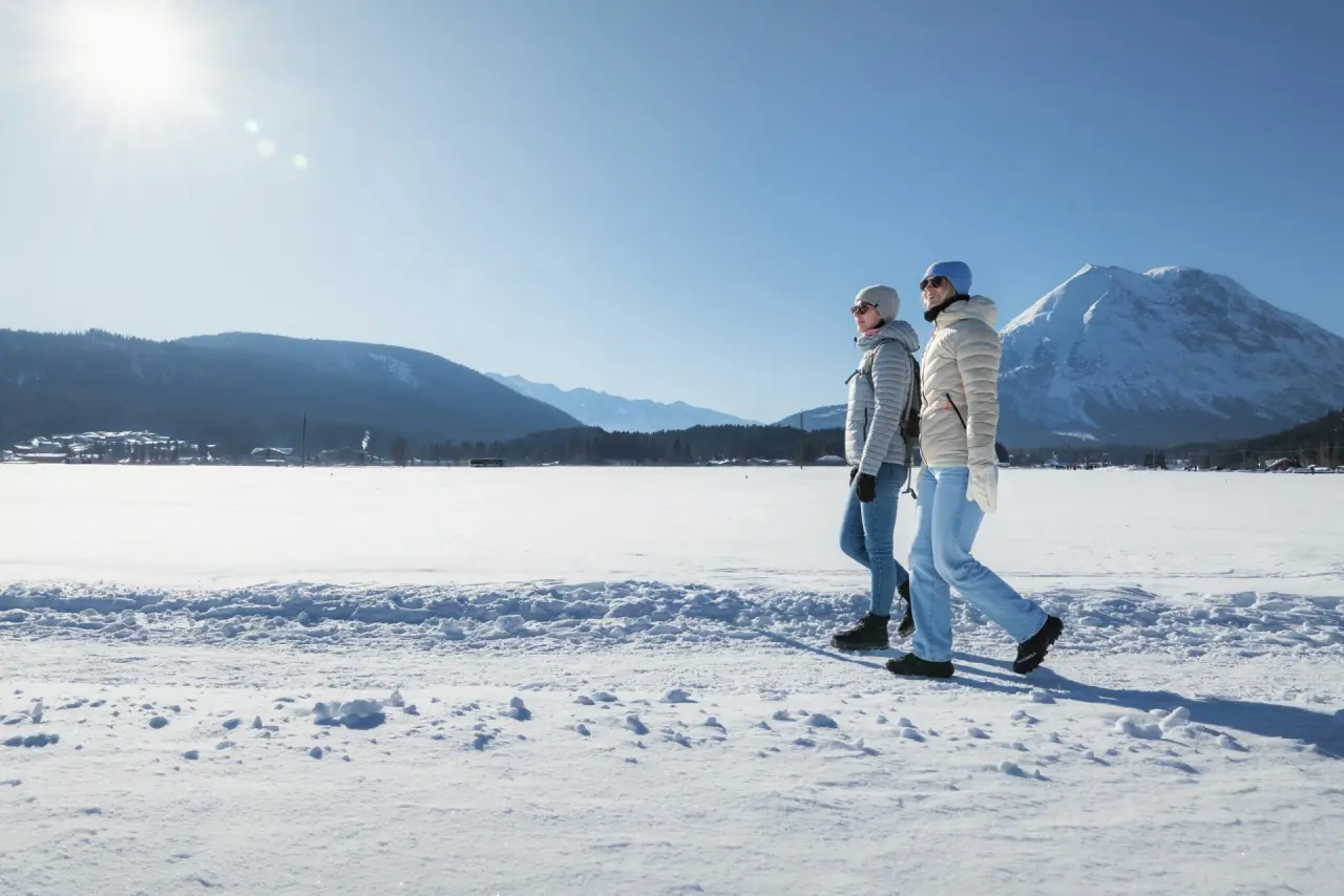 Winterwanderung mit Bergblick für Gäste des Hotel Eden. Zwei Personen genießen die verschneite Landschaft unter blauem Himmel.