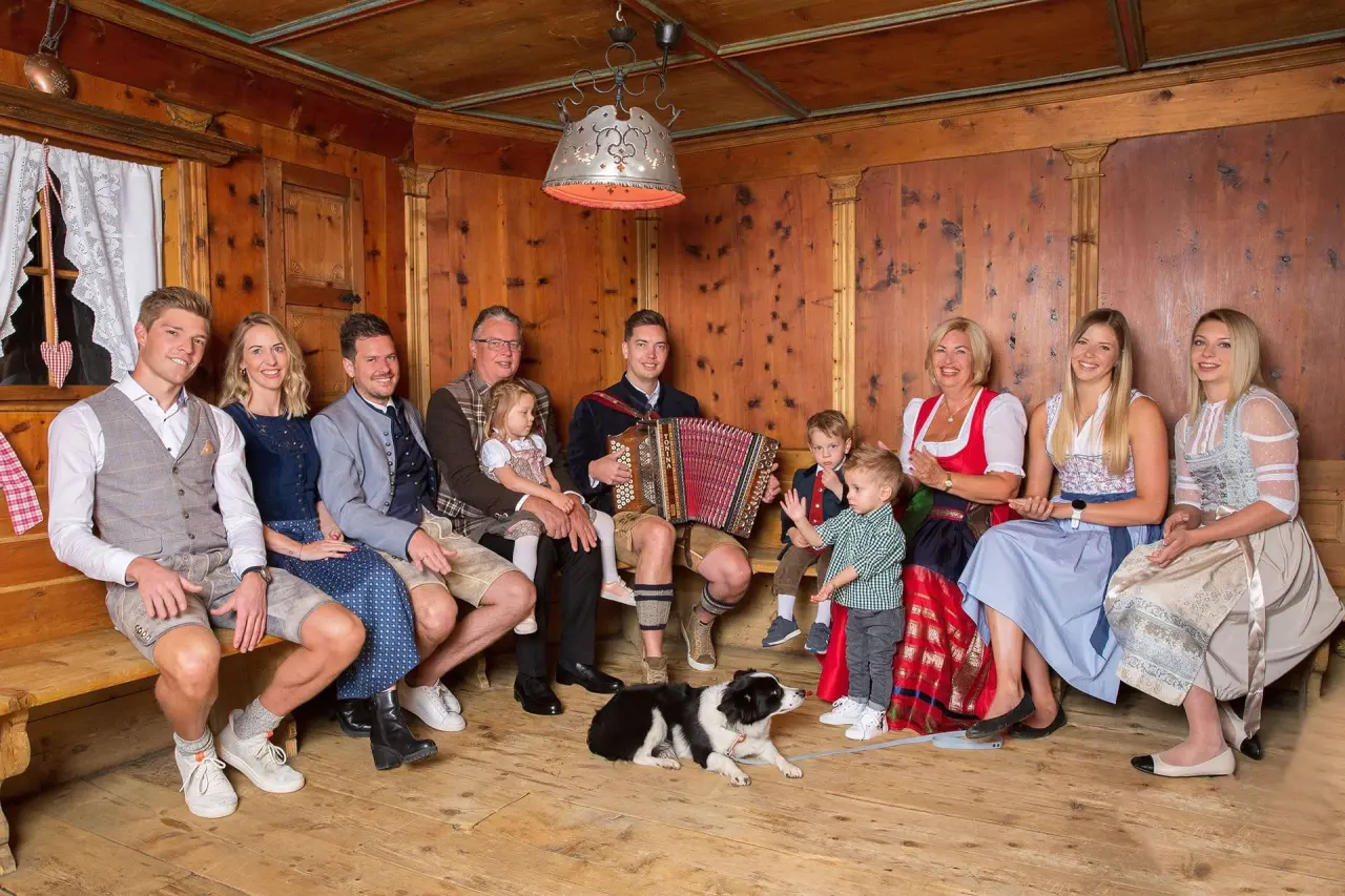 Familie des Wellnesshotels ...liebes Rot-Flüh in Tracht in einer traditionellen Holzstube mit Akkordeon und Hund.