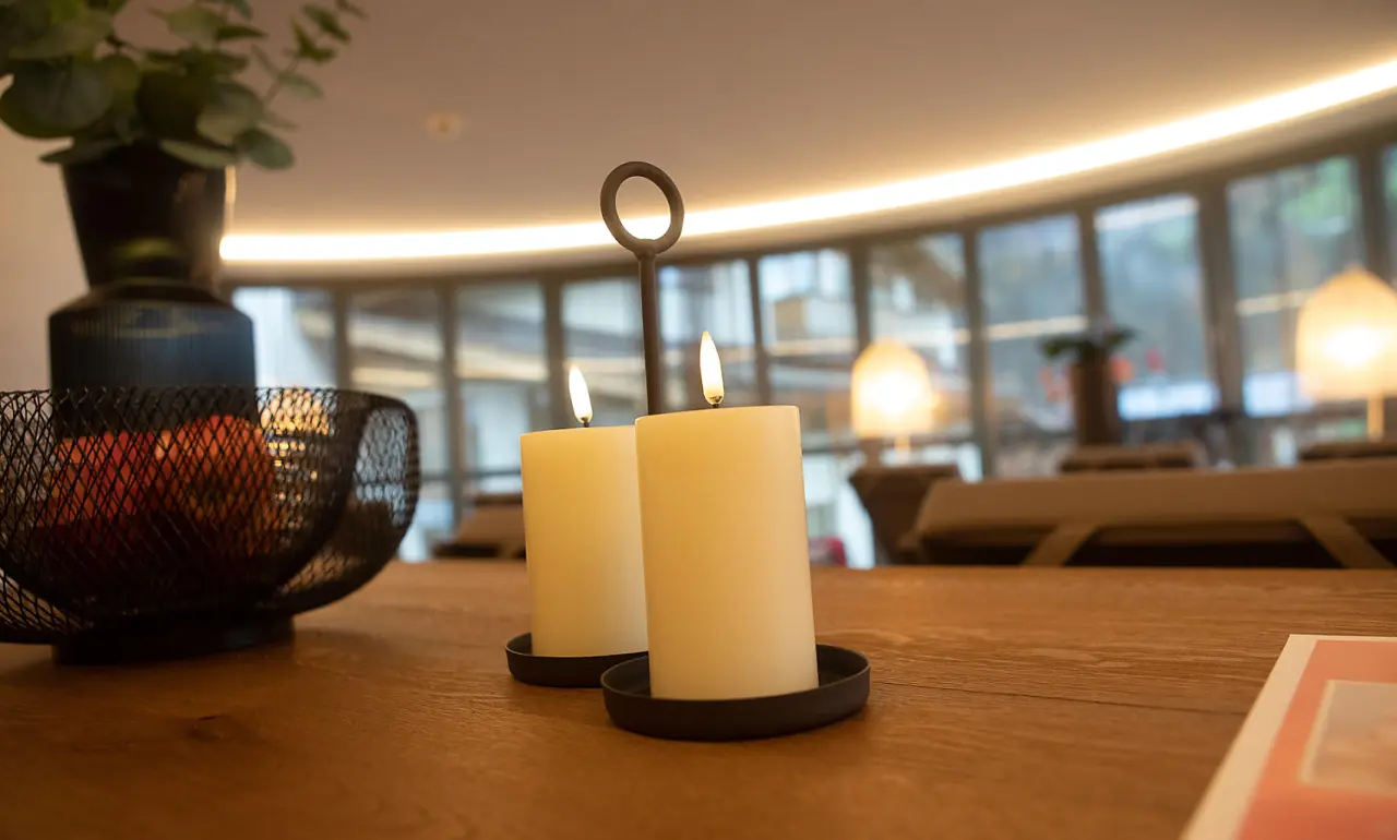 Warme Kerzenbeleuchtung und frisches Obst auf Holztisch im gemütlichen Ambiente des Hotel Elisabeth Tirol.