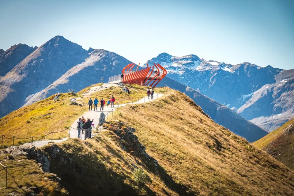 Wanderer auf einem Bergpfad mit moderner Aussichtsplattform und weitem Alpenpanorama nahe dem sonnenhotel ZUM STERN.