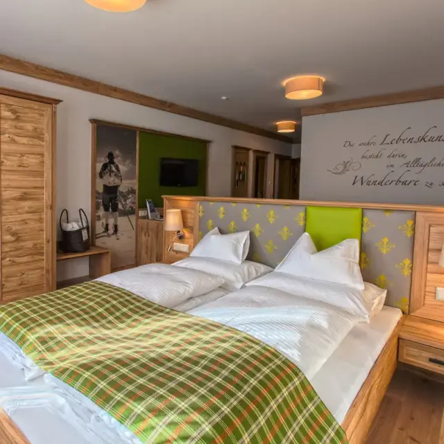 Gemütliches Doppelzimmer im alpenländischen Stil mit Holzelementen und karierter Decke im Sonnenhotel ZUM STERN.