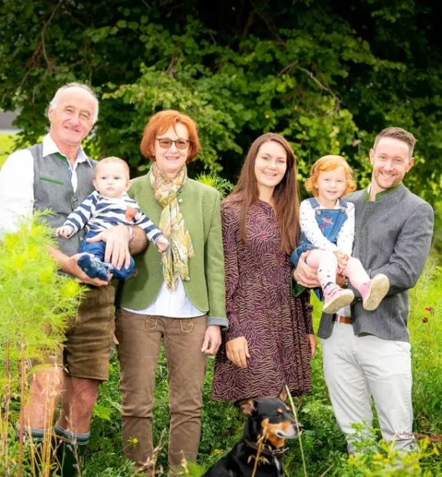Familie Schörhof mit Hund im grünen Garten des Wellnesshotels Schörhof