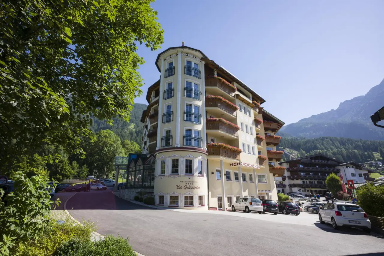Aussenansicht des Wellnesshotels Vier Jahreszeiten in den Bergen mit blühenden Balkonen und sonnigem Wetter.