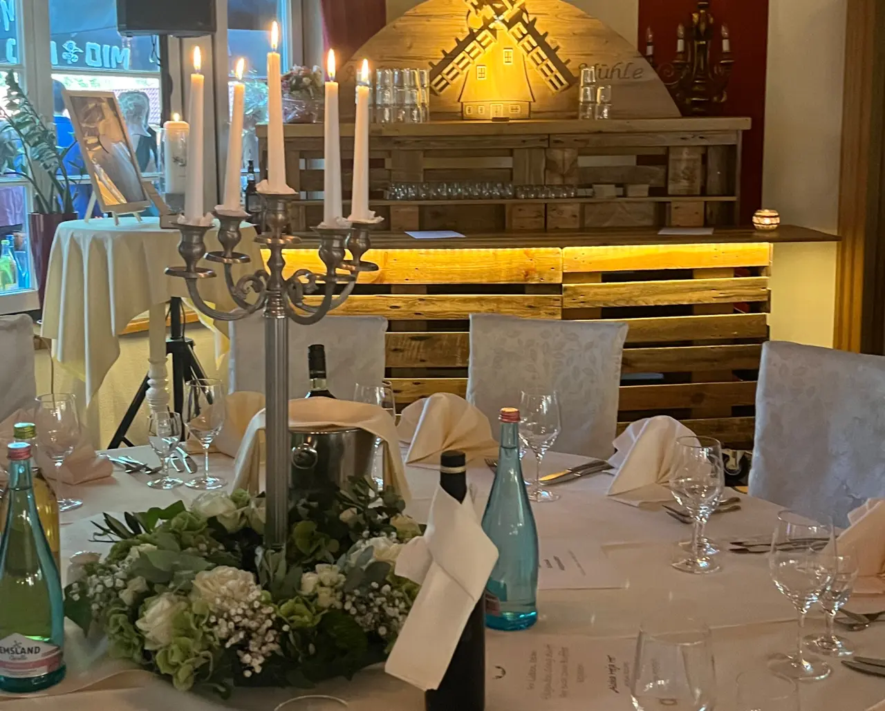 Festlich gedeckter Tisch mit Kerzenleuchter und Blumenkranz im Restaurant des Romantik Hotel Aselager Mühle.