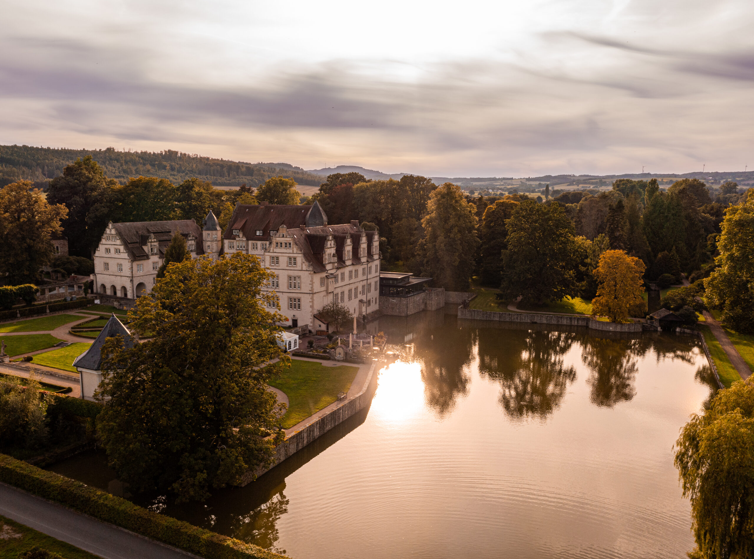 Schlosshotel Münchhausen in Aerzen – Schlossanlage mit See bei Sonnenuntergang | Wellnesshotel Weserbergland