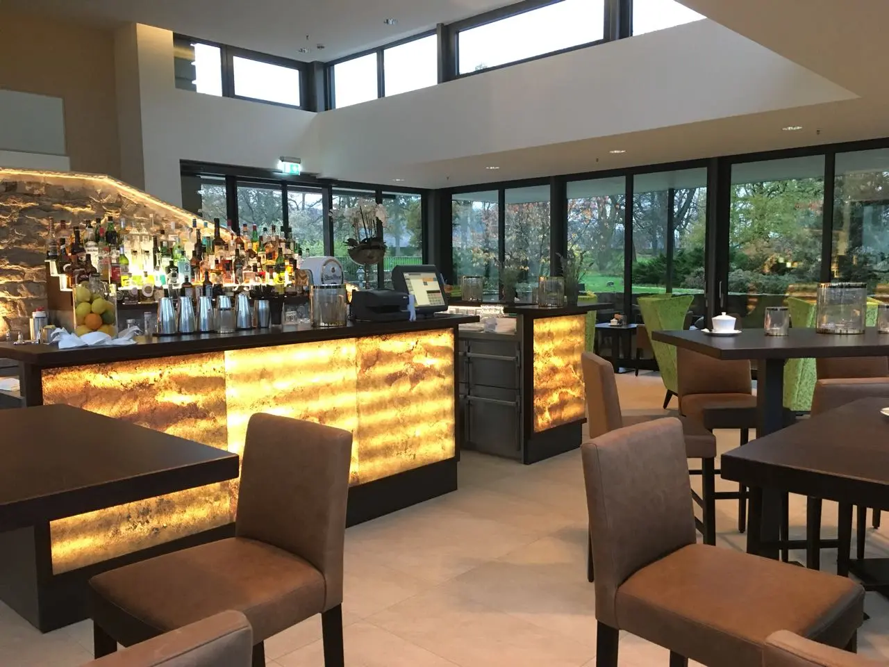 Schlosshotel Münchhausen in Aerzen – Moderne Bar mit beleuchteter Theke und Gartenblick | Wellnesshotel Weserbergland