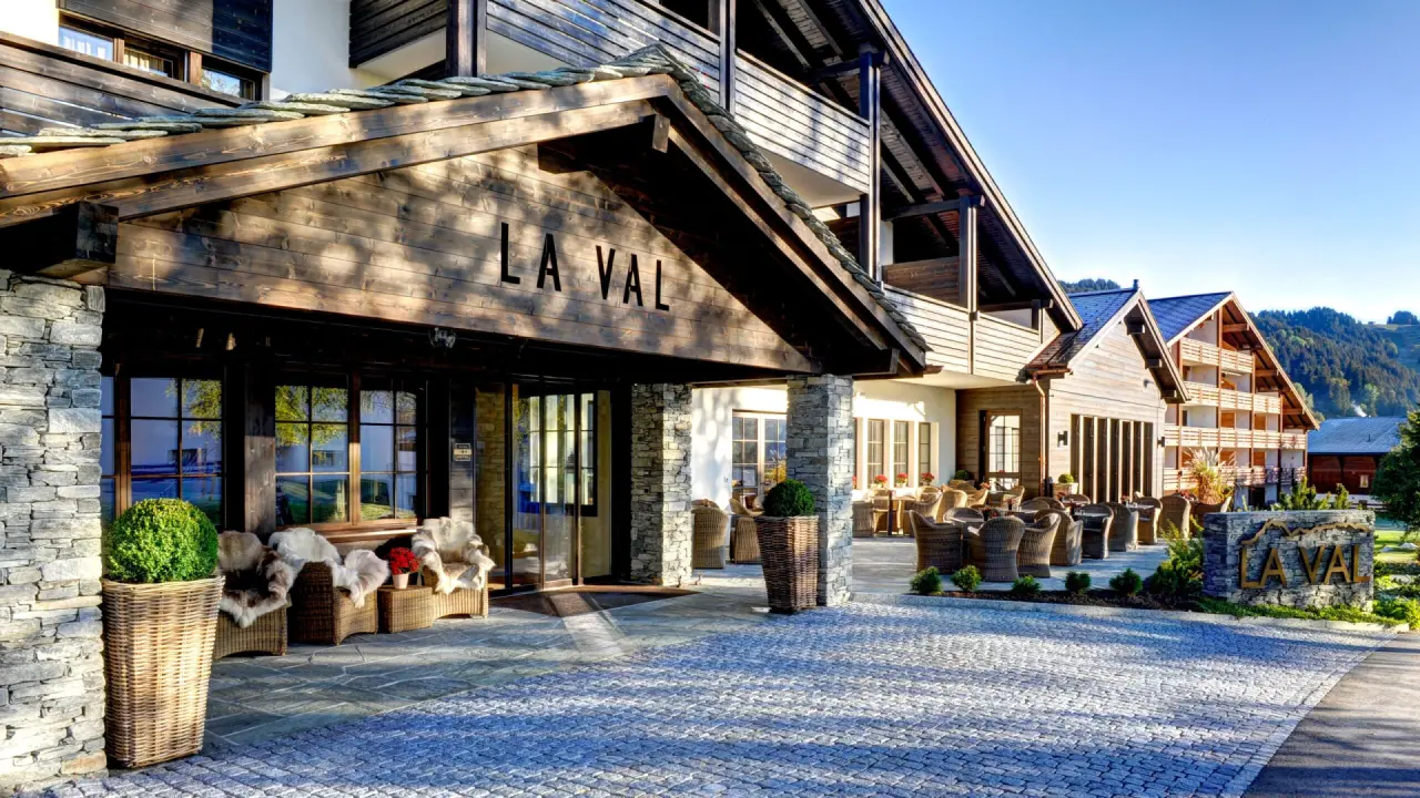 Eingangsbereich des La Val Hotel & Spa mit alpiner Architektur, Steinmauern und sonniger Terrasse.