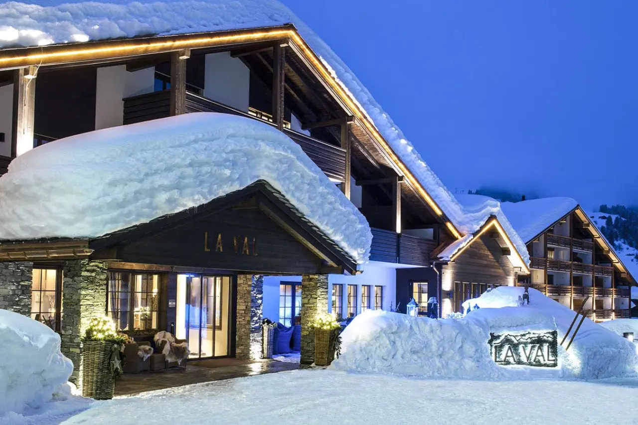 Winterliche Aussenansicht des La Val Hotel & Spa bei Dämmerung, mit verschneiten Dächern und warm beleuchtetem Eingangsbereich.