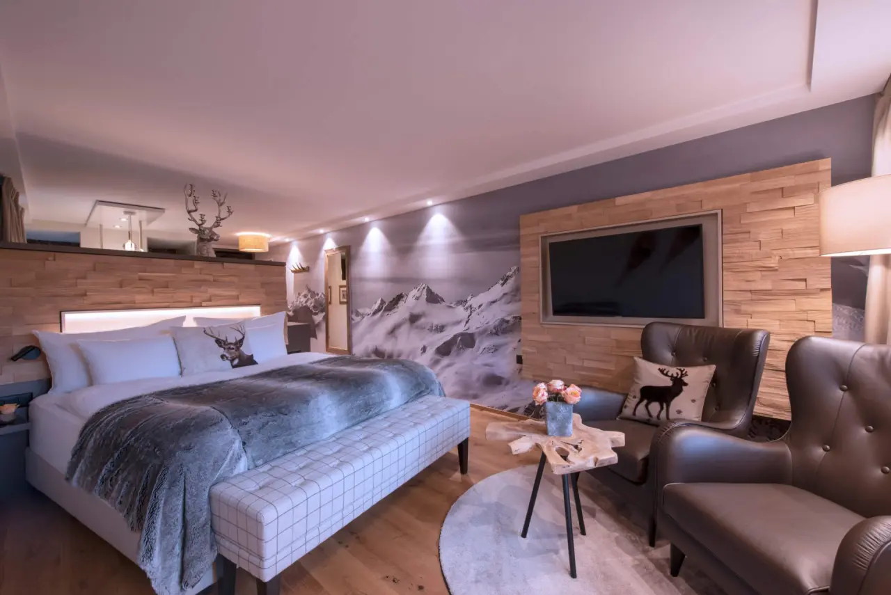 Gemütliches Doppelzimmer im alpinen Stil mit Bergblick-Wandbild und Holzelementen im La Val Hotel & Spa.