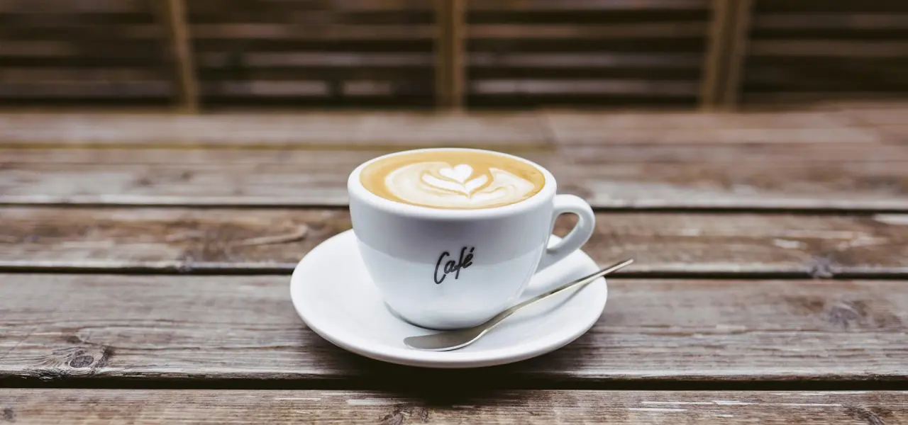 Kaffee mit Herz-Latte Art auf rustikalem Holztisch im Naturresort & Spa Schindelbruch.