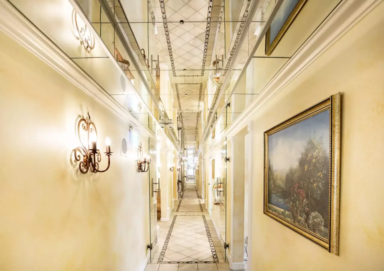 Eleganter Hotelflur mit Spiegeldecke, Wandleuchten und Kunst im Hotel Schweizer Hof Betriebs-GmbH.