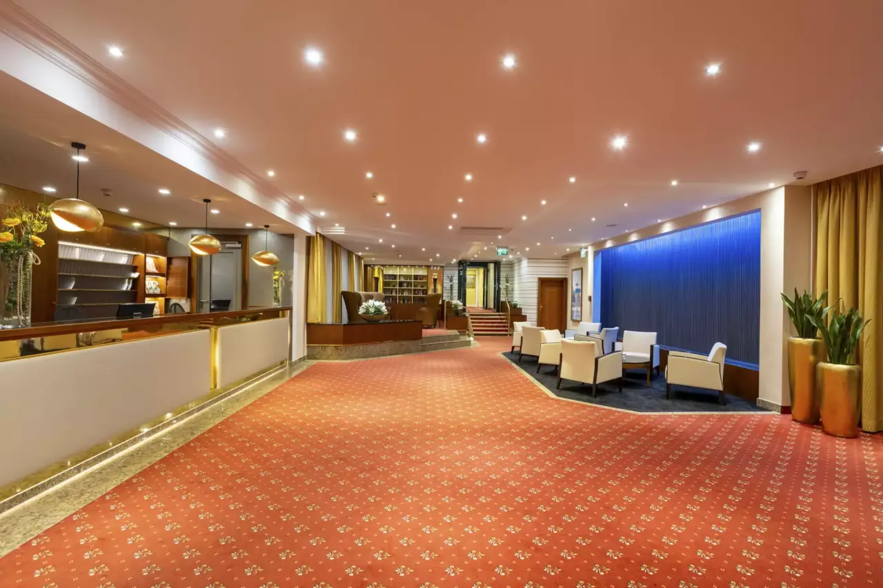 Einladende Lobby des Hotel Schweizer Hof Betriebs-GmbH mit Rezeption, Sitzbereichen und blauer Akzentwand.