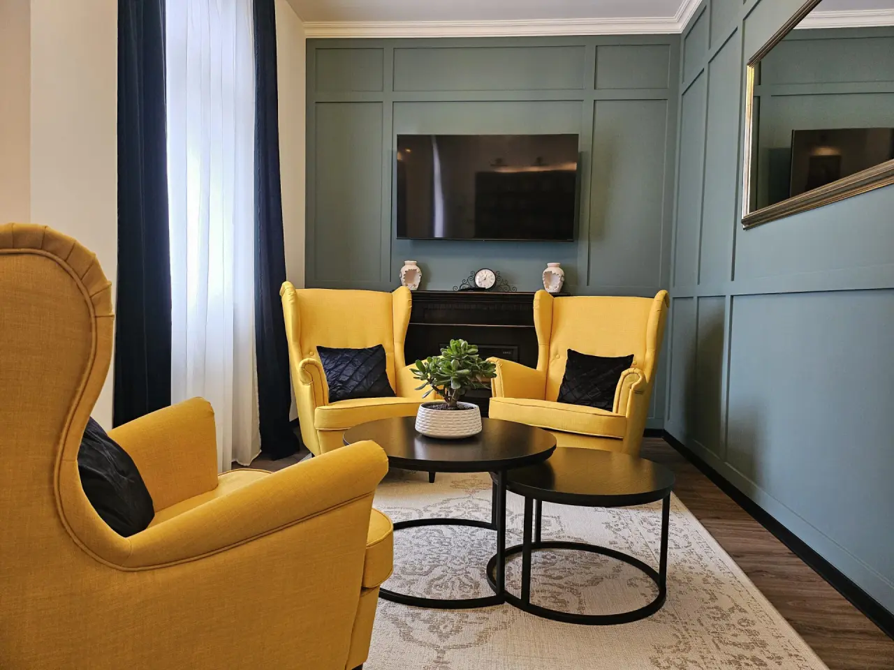 Moderne Hotellounge im Hotel Flora mit gelben Sesseln, Holzwand und Flachbildschirm für entspannte Stunden.