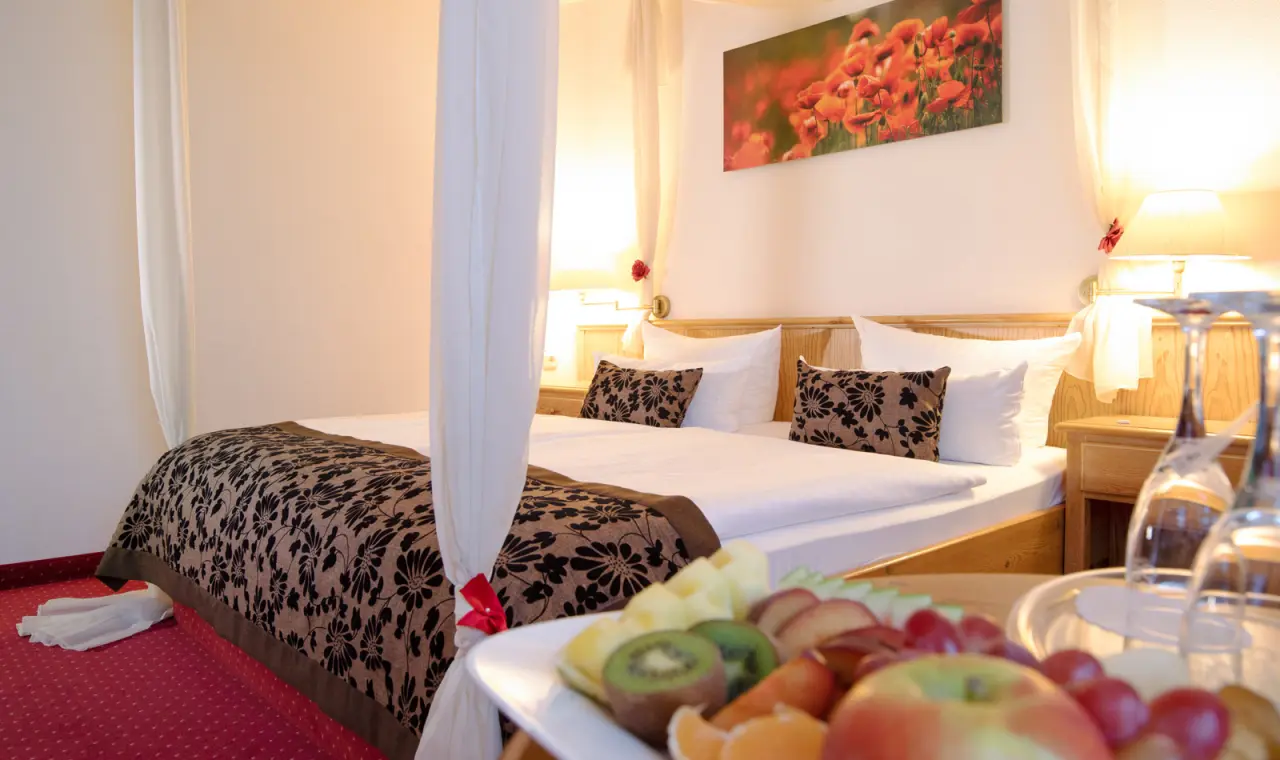 Komfortables Doppelzimmer mit Himmelbett und frischem Obst im Hotel Flora