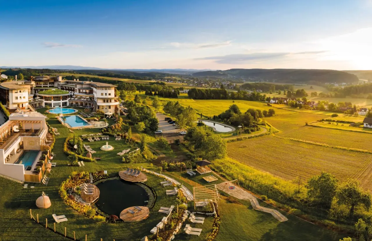 Luftaufnahme des Wellnesshotels Larimar: Weitläufige Anlage mit Pools, Garten und idyllischer Landschaft im Abendlicht.