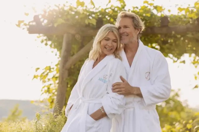 Glückliches Paar in Larimar Bademänteln genießt die Abendsonne im Hotelgarten. Ideal für Wellness-Urlaub.