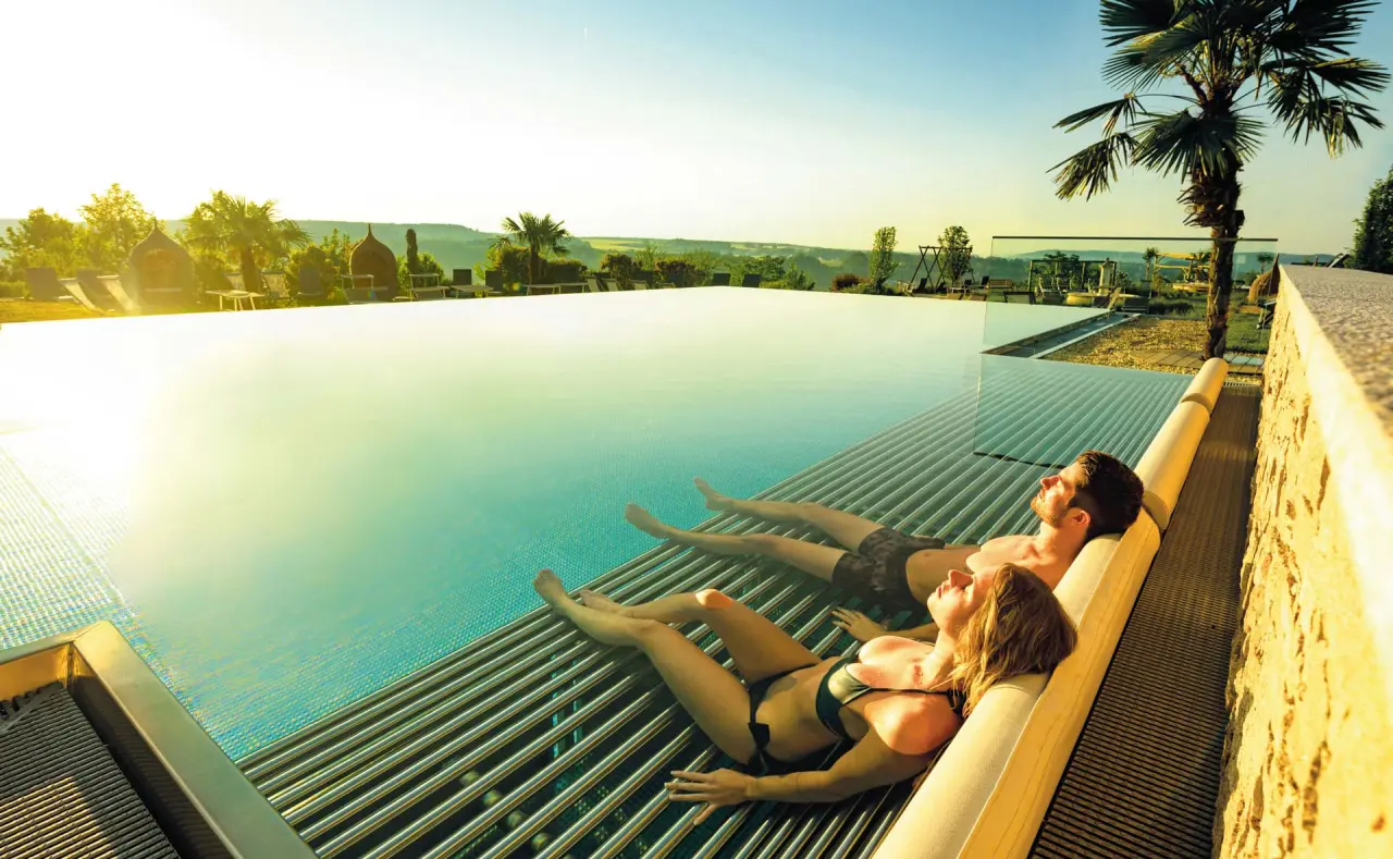 Paar entspannt auf Unterwasserliegen im Infinity Pool des Hotel Larimar mit Panoramablick.