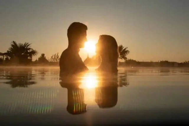 Romantischer Sonnenuntergang im warmen Pool des Hotel Larimar. Ein Paar genießt den Ausblick, Palmen im Hintergrund.