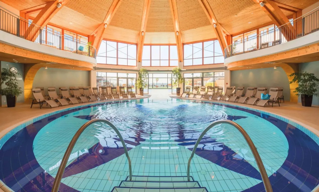 Grosszügiger Innenpoolbereich im Hotel Larimar mit Holzkuppel, vielen Liegen und grossen Fenstern für viel Tageslicht.