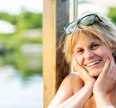 Lachende Frau mit Sonnenbrille im Avita Resort****Superior, die Entspannung und Wohlbefinden ausstrahlt.