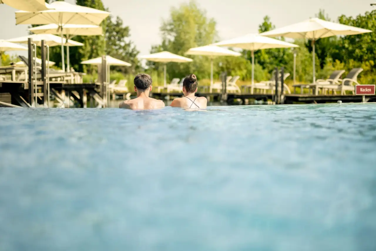 Paar entspannt im Aussenpool des Avita Resort****Superior mit Blick auf die Liegebereiche und Sonnenschirme.