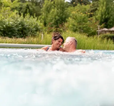 Paar genießt entspanntes Bad im sprudelnden Whirlpool des Avita Resort****Superior, umgeben von Natur.