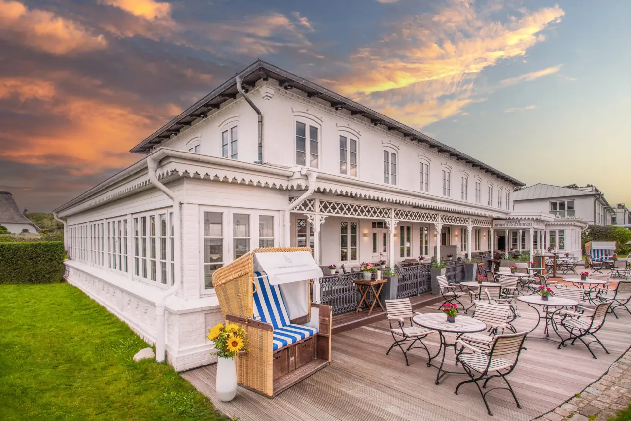 Charmantes Fährhaus Sylt Hotel mit Terrasse, Strandkorb und Abendhimmel.
