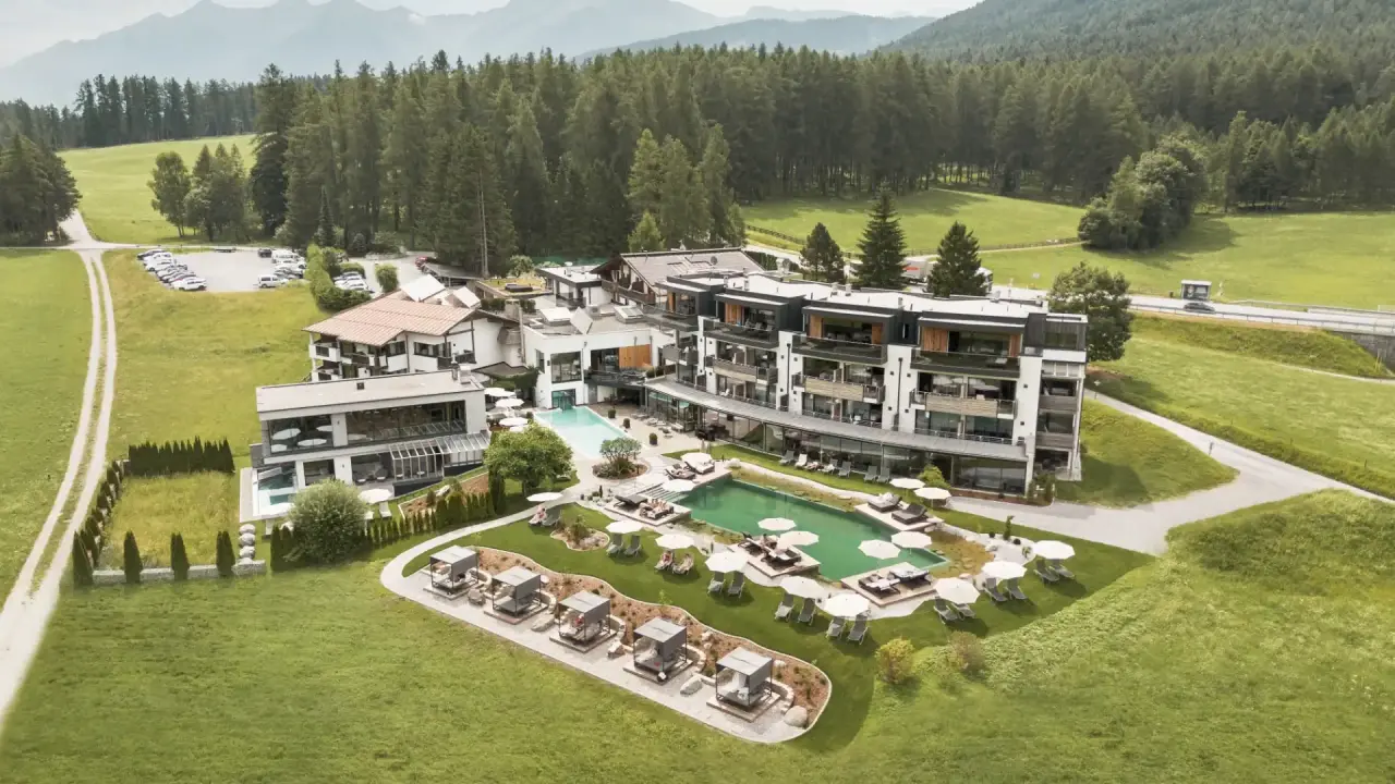 Luftaufnahme des Holzleiten Bio Wellness Hotels mit Aussenpools, Liegewiesen und Bergpanorama in grüner Natur.