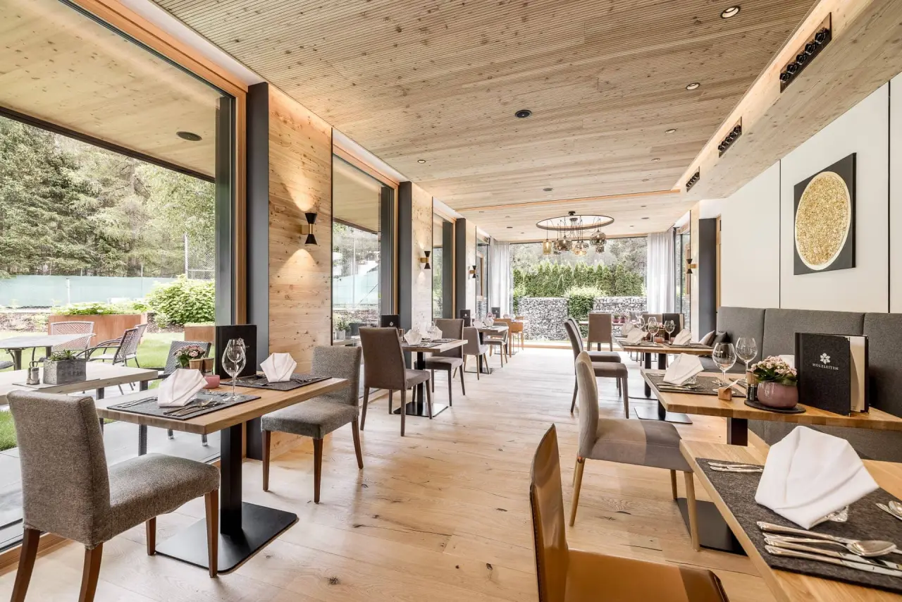 Modernes Restaurant mit Holzelementen und grossen Fenstern mit Blick ins Grüne im Holzleiten Bio Wellness Hotel.