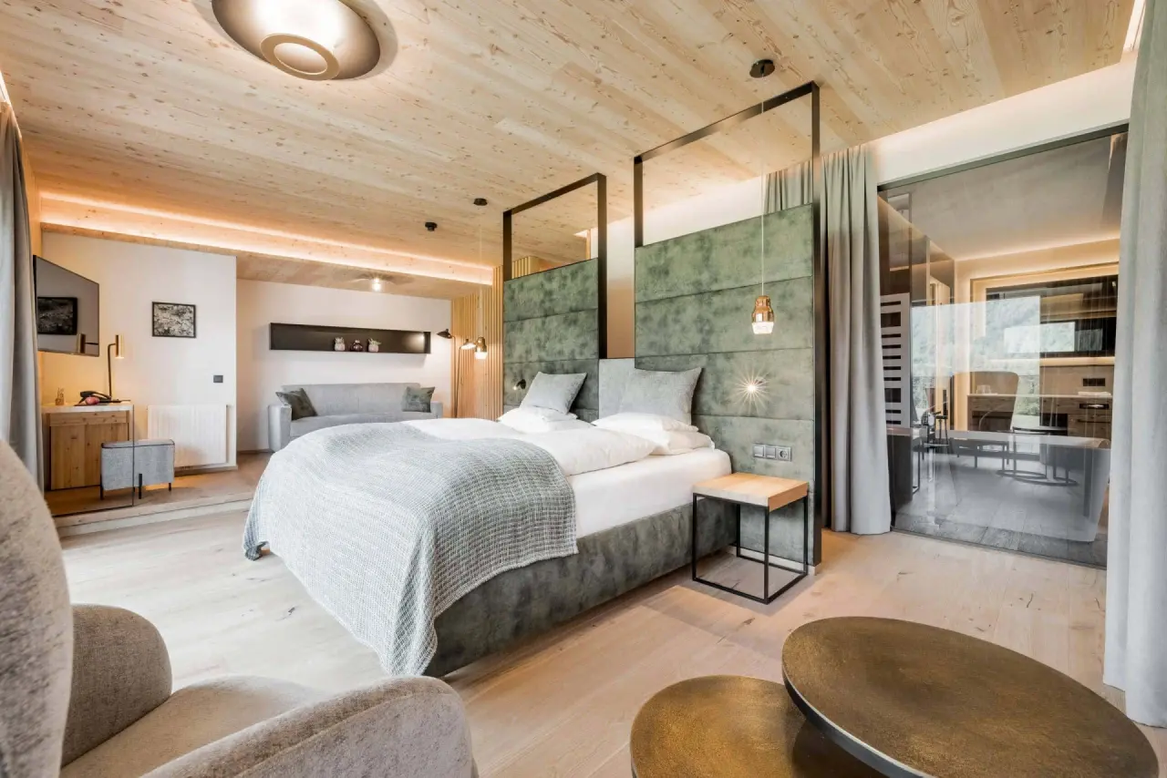 Modernes Doppelzimmer im Holzleiten Bio Wellness Hotel mit Holzelementen, gemütlichem Bett und Sitzbereich.