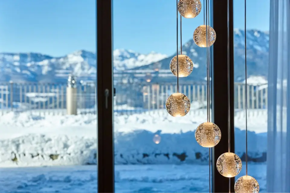 Stilvolle Hängelampen mit Blick auf die winterliche Bergwelt des Kempinski Hotel Berchtesgaden.