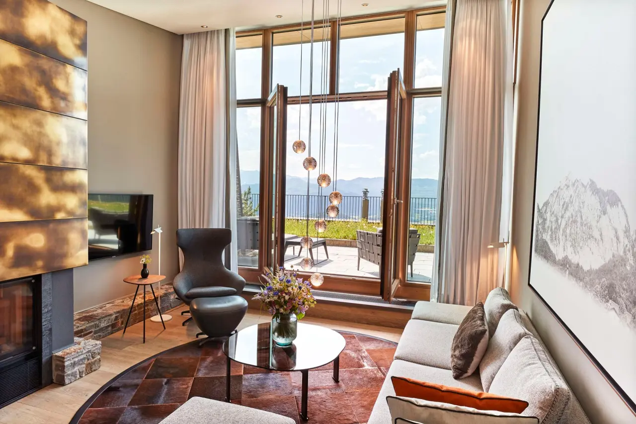 Luxuriöses Wohnzimmer einer Suite mit Kamin und Bergblick im Kempinski Hotel Berchtesgaden
