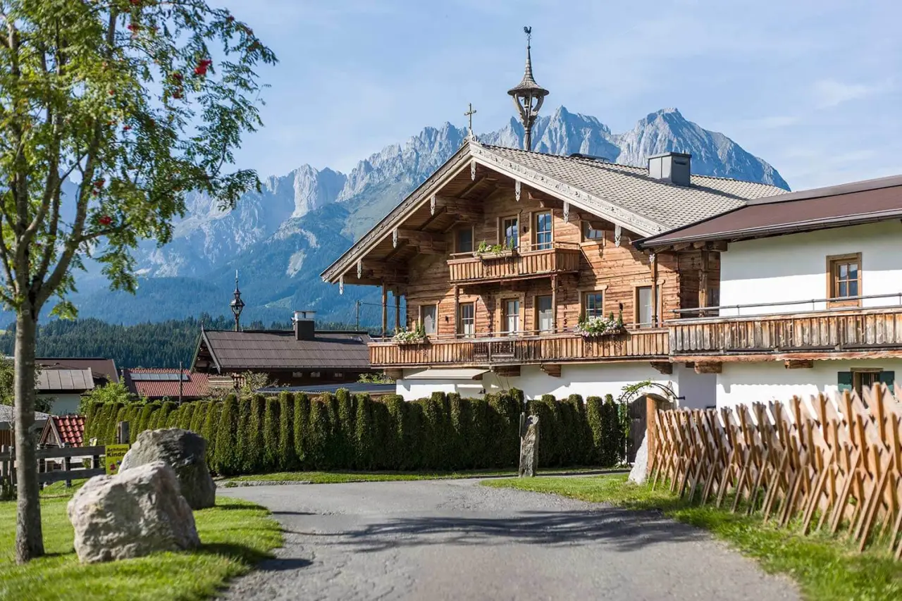 Traditionelles Hotel Penzinghof mit Holzbalkonen und beeindruckendem Bergpanorama der Kitzbüheler Alpen.