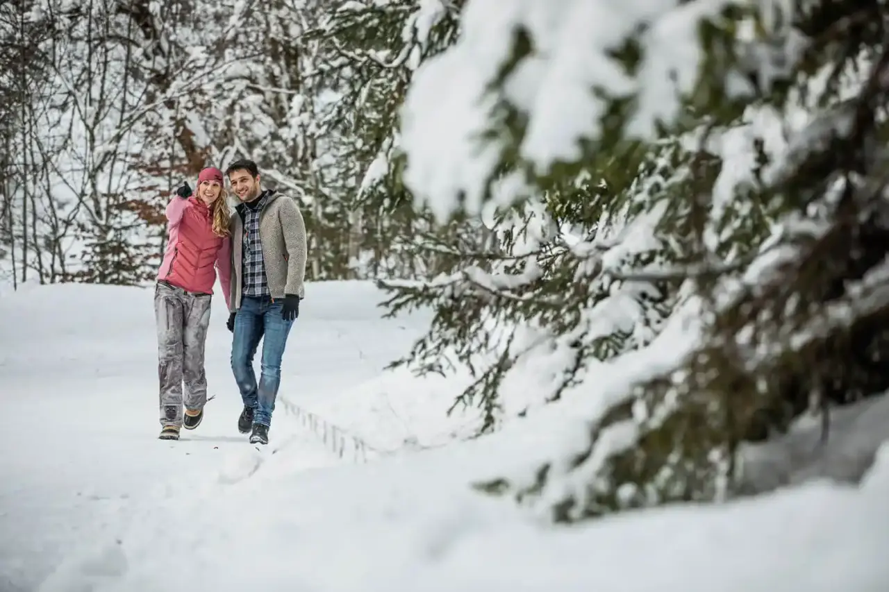 Glückliches Paar beim Winterspaziergang im verschneiten Wald nahe dem Hotel Penzinghof, ideal für aktive Erholung.