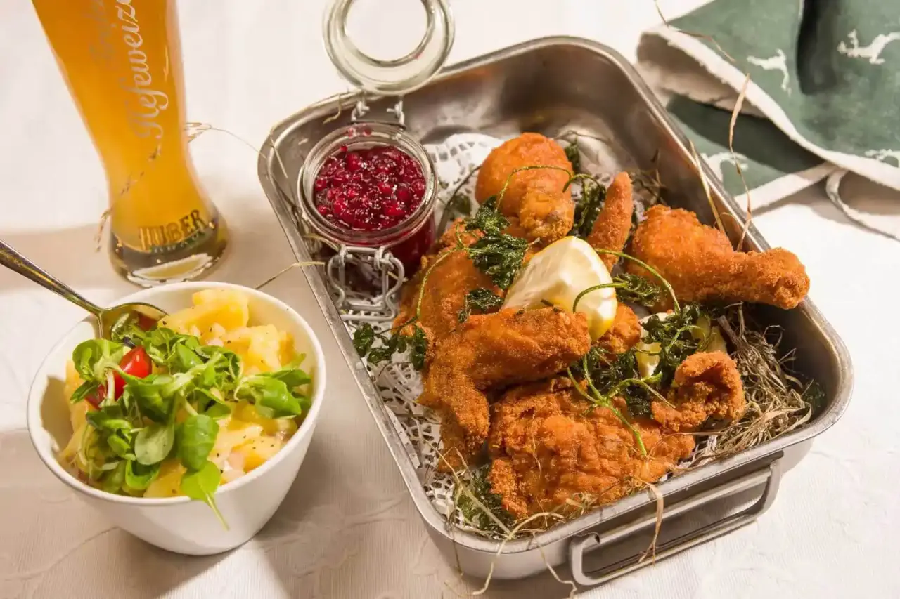 Knuspriges Backhendl mit Kartoffelsalat, Preiselbeeren und Weizenbier im Restaurant des Hotel Penzinghof.