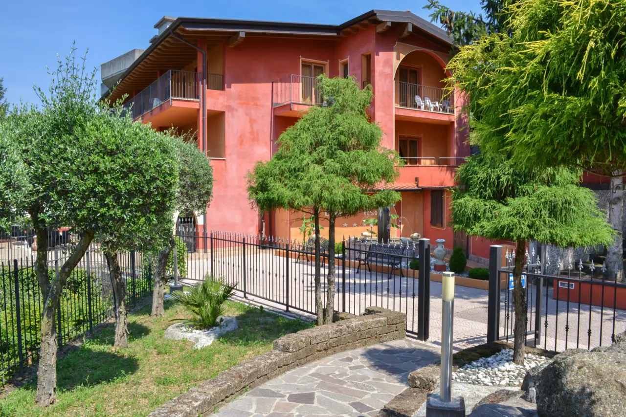 Empire Resort in Garda – Mediterrane Außenansicht mit roter Fassade und Garten | Wellnesshotel Gardasee