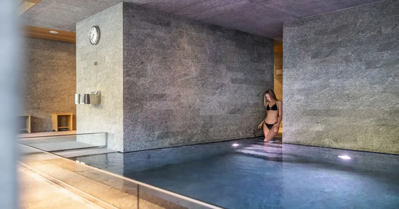 Moderne Innenpool-Anlage mit Natursteinwänden und entspannender Atmosphäre im Design & Wellness Hotel Alpenhof.