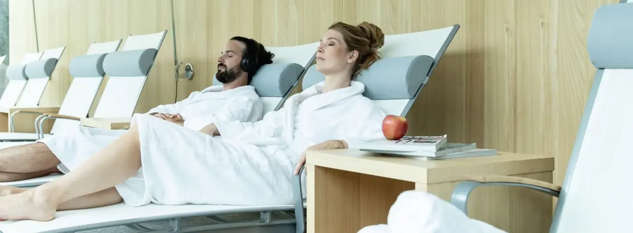 Gäste entspannen in Bademänteln auf Liegen im Ruheraum des Design & Wellness Hotel Alpenhof.