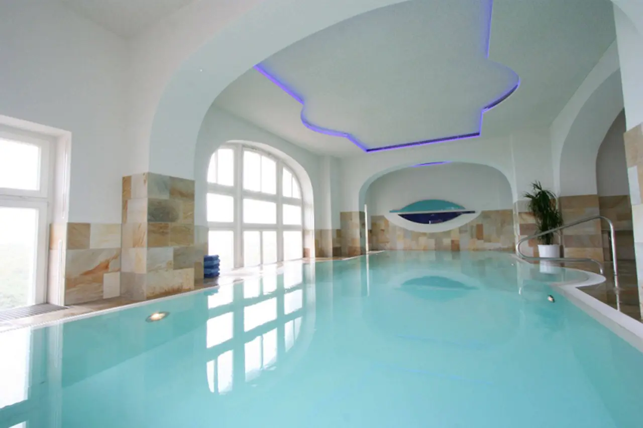 Grosszügiger Innenpool mit Tageslicht und stilvoller Beleuchtung im Strandhotel Kurhaus Juist.