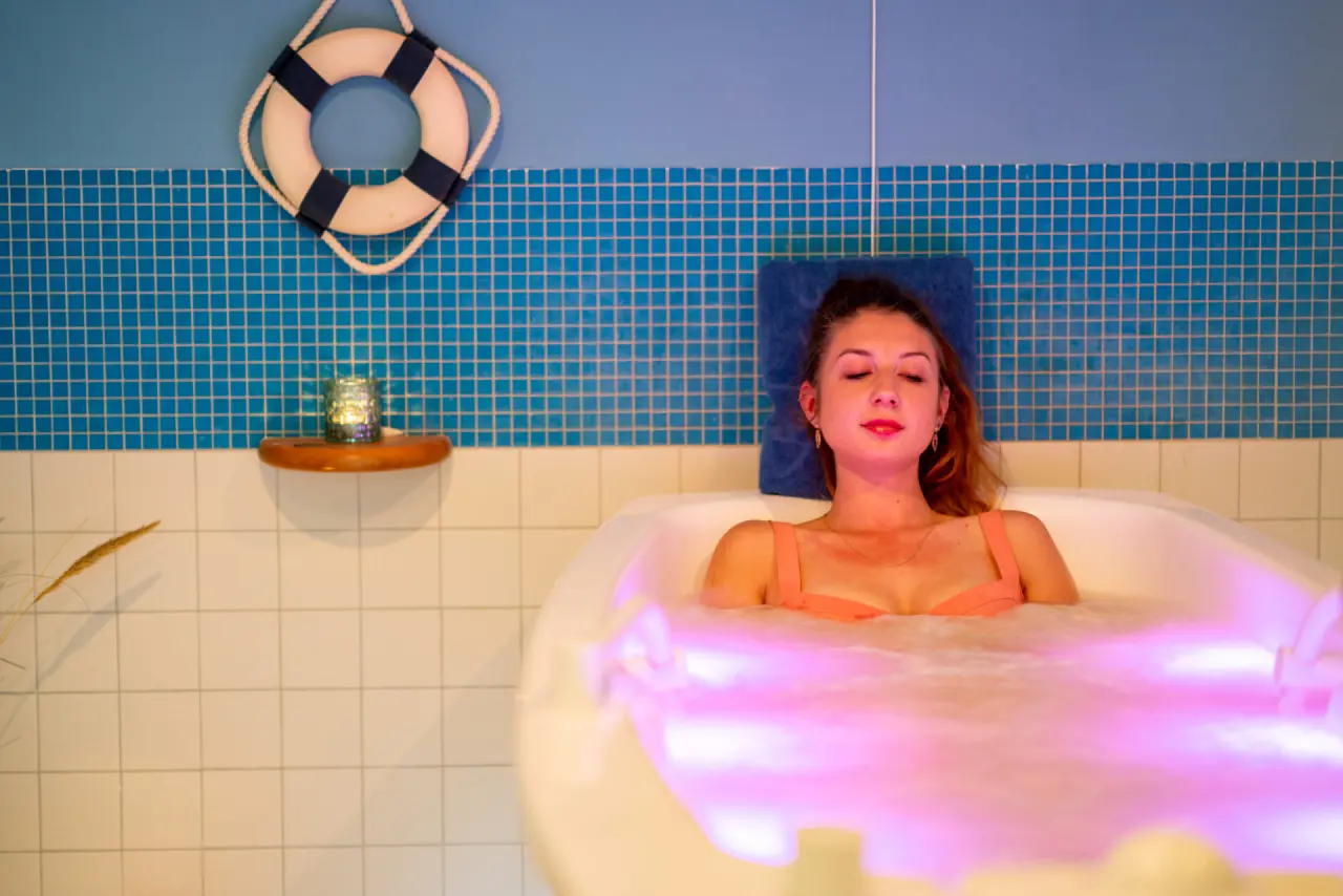 Entspannendes Farblichtbad im Hydro-Spa des Strandhotel Kurhaus Juist. Eine Frau genießt die wohltuende Atmosphäre.