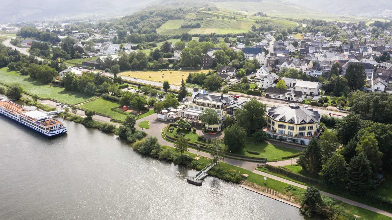 Luftaufnahme des Hotel Weisser Bär an der Mosel mit Fluss, grünen Weinbergen und umliegender Landschaft.