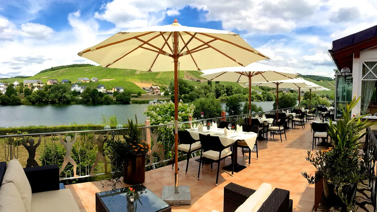 Sonnige Restaurantterrasse des Hotel Weisser Bär mit Blick auf die Mosel und die umliegenden Weinberge.