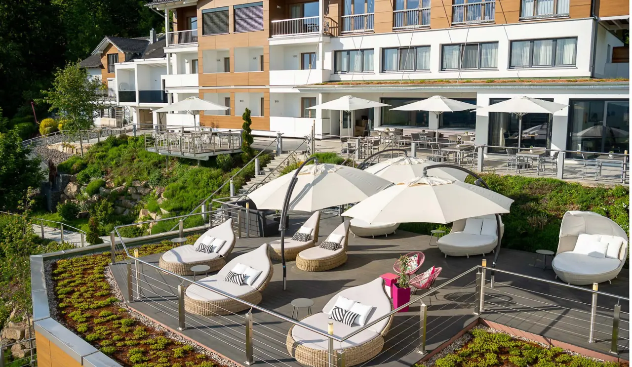 Terrassierte Aussenanlage mit luxuriösen Daybeds und Sonnenschirmen am Thula Wellnesshotel Bayerischer Wald.