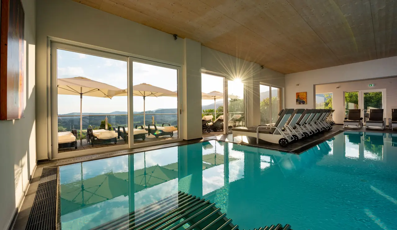 Heller Innenpool mit Liegen und Panoramablick auf den Bayerischen Wald im Thula Wellnesshotel.